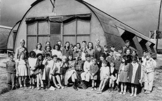 Class photo of students in front of Quonset hut
